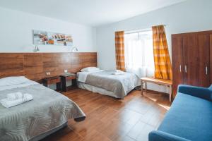 サン・ペドロ・デ・アタカマにあるPeumayen Atacama cabaña&Hostalのベッド2台とソファが備わるホテルルームです。