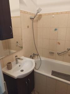 ein Badezimmer mit einem Waschbecken, einer Dusche und einer Badewanne in der Unterkunft Áron Apartman Pécs in Pécs