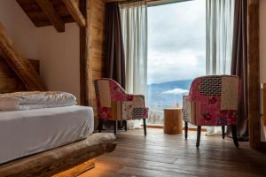 a bedroom with a bed and two chairs and a large window at Casera Cornolera in Chies dʼAlpago
