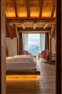 a bedroom with a bed and a large window at Casera Cornolera in Chies dʼAlpago