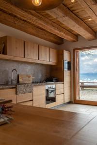 una cocina con armarios de madera y una gran ventana en Casera Cornolera en Chies dʼAlpago