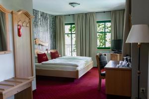ein Hotelzimmer mit einem Bett, einem Schreibtisch und Fenstern in der Unterkunft Landgasthof zum Mühlenteich in Eggersdorf