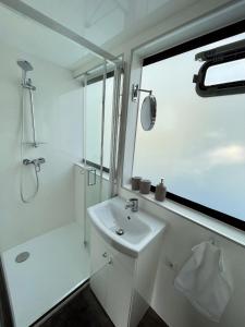 a white bathroom with a sink and a shower at KL Moselboote - Hausboot Niara in Bernkastel-Kues