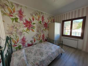 1 dormitorio con 1 cama con flores en la pared en Appartamento in villa a 20 min da Levanto e dalle 5 Terre-Sesta Godano en Sesta Godano