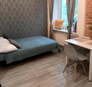 a room with a bed and a table and a desk at Hola Apartamenty Legionow 2 in Łódź