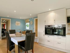 a kitchen with white cabinets and a table with chairs at Wandale Barn in Slingsby