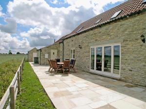 a patio with chairs and a table next to a building at Wandale Barn in Slingsby