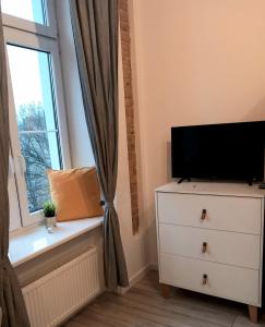 a bedroom with a tv on a dresser and a window at Hola Apartamenty Legionow 2 in Łódź
