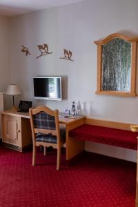 a hotel room with a desk and a bed and a table at Landgasthof zum Mühlenteich in Eggersdorf
