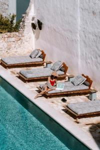 a woman is sitting on a lounge chair next to a swimming pool at Paragon 700 Boutique Hotel & SPA in Ostuni