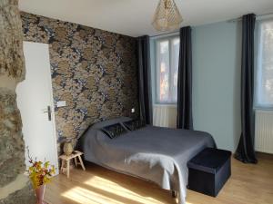 ein Schlafzimmer mit einem Bett in einem Zimmer mit Tapete in der Unterkunft Au Pied de la Béalière in Montpezat-sous-Bauzon