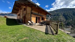 a log cabin on a hill with a wooden deck at L'ourson in Le Grand-Bornand