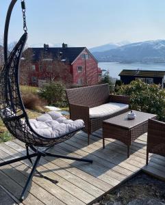 a swinging chair and a table on a deck at Great place with view to the mountains and fjord in Ålesund