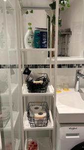 a bathroom with white shelves and a sink at AA Apartment in Ventspils