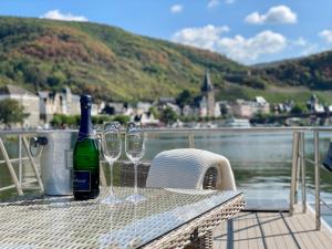 a bottle of wine and two wine glasses sitting on a table at KL Moselboote - Hausboot Neptun in Bernkastel-Kues