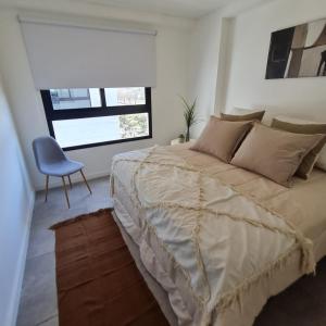 ein Schlafzimmer mit einem großen Bett und einem blauen Stuhl in der Unterkunft Temponorte Salta II in Salta