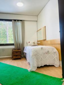 a bedroom with a white bed and a green rug at Voionmaa Voionmajoitus in Ylöjärvi