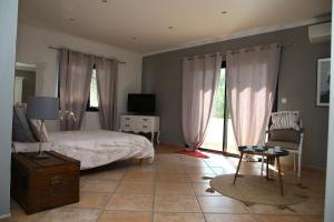 1 dormitorio con 1 cama, TV y silla en La Villa Blanche, en Sanary-sur-Mer