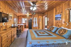 a bedroom in a log cabin with a bed and a kitchen at Hidden Rest Cabins and Resort in Lake of the Woods