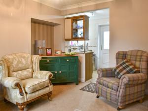 a living room with two chairs and a green cabinet at North Cottage in Heighington