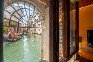 einen Blick aus einem Fenster auf einen Kanal mit einer Gondel in der Unterkunft Casa Flavia ai Morosini - Luxury apartment with Canal View in Venedig