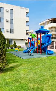 einen Spielplatz im Gras vor einem Gebäude in der Unterkunft Resort Leon Beach in Mamaia Nord – Năvodari