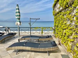 2 Betten auf einer Terrasse mit Sonnenschirm und Meer in der Unterkunft Hotel Estée in Desenzano del Garda