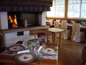 a table with plates and wine glasses and a fireplace at Rifugio Monti Pallidi in Canazei