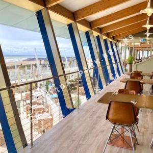 a restaurant with tables and chairs and a view of the ocean at Cosy Cove at Seal Bay - 2 Bedroom Holiday Home on White Horse in Selsey