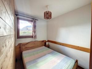 um pequeno quarto com uma cama e uma janela em Appartement 1 chambre avec garage em Praz-sur-Arly