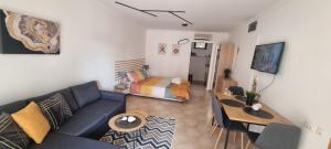 a living room with a blue couch and a bed at Eve Santa Marina Studios - sea, pools, relax in Sozopol