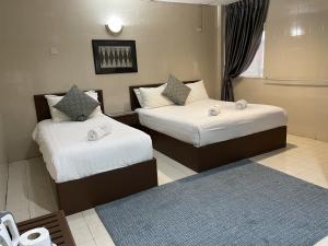 a hotel room with two beds and a blue rug at Barrack Street Hotel in Taiping