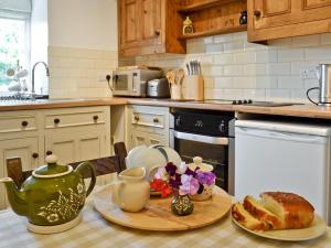 a kitchen with a table with a tea pot and bread at Dylasau Cottage in Capel Garmon
