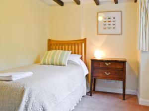 a small bedroom with a bed and a night stand at Dylasau Cottage in Capel Garmon