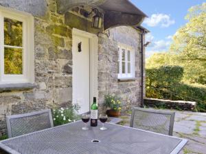 a table with two glasses of wine on a patio at Dylasau Cottage in Capel Garmon