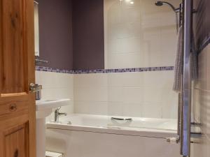 La salle de bains est pourvue d'une baignoire blanche et d'un lavabo. dans l'établissement Sunny Dales Townhouse, à Settle