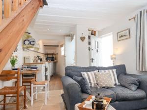 un salon avec un canapé bleu et une cuisine dans l'établissement Honeymoon Cottage, à Bideford