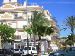 a tall white building with palm trees in front of it at Costa del Sol in Málaga