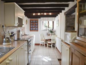 a kitchen with white cabinets and a table with chairs at Yet Farm Cottage in Cenarth