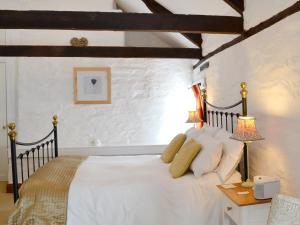 a bedroom with a large white bed and a table at Yet Farm Cottage in Cenarth