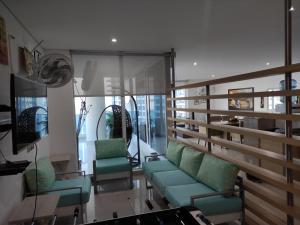 sala de estar con sillas verdes y TV en Apartamento Reserva del Mar, en Santa Marta