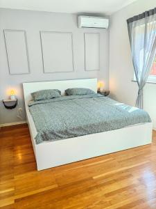 a white bed in a white bedroom with wood floors at Zelena oaza 300 metara od mora in Banjole