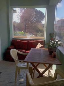 a table and chairs in a living room with a window at Lil' fam farm home - Beach 10min in Agios Ioannis