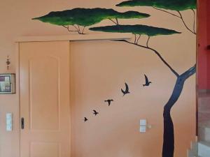 un mural de un árbol y aves en una pared en Lil' fam farm home - Beach 10min, en Ágios Ioánnis