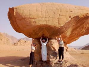 three people holding up a rock in the desert at Welcome to Wadi Rum Camp in Wadi Rum