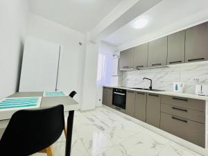 a white kitchen with a table and a sink at Altheda Living White House 29F-2 in Suceava