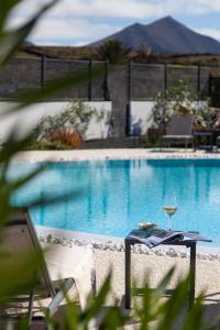 a table with a glass of wine next to a swimming pool at Mana EcoRetreat in Las Breñas