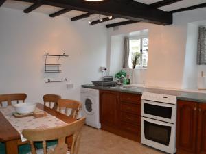 a kitchen with a table and a sink and a dishwasher at 2 Town Head Cottages in Grasmere