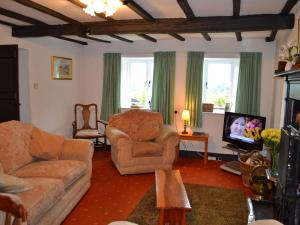 a living room with a couch and chairs and a tv at 2 Town Head Cottages in Grasmere