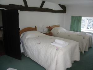 two beds in a bedroom with white sheets and towels at 2 Town Head Cottages in Grasmere